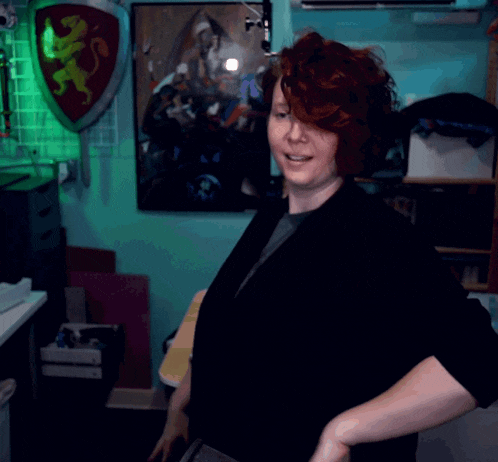 a woman with red hair is standing in front of a lion shield
