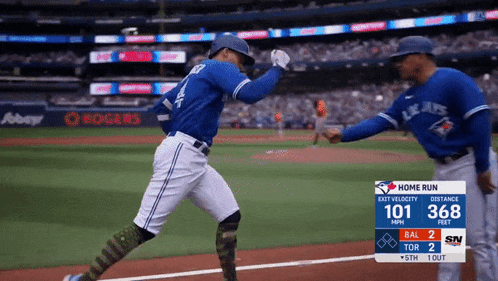 two blue jays baseball players giving each other a high five on the field
