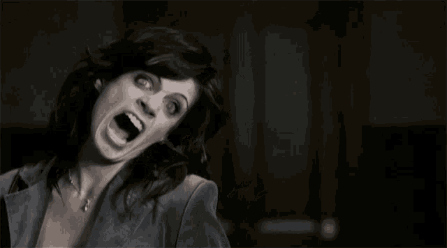 a woman in a blue jacket is screaming with her mouth wide open