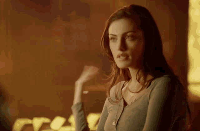 a woman in a dark room looks at the camera with a serious look on her face