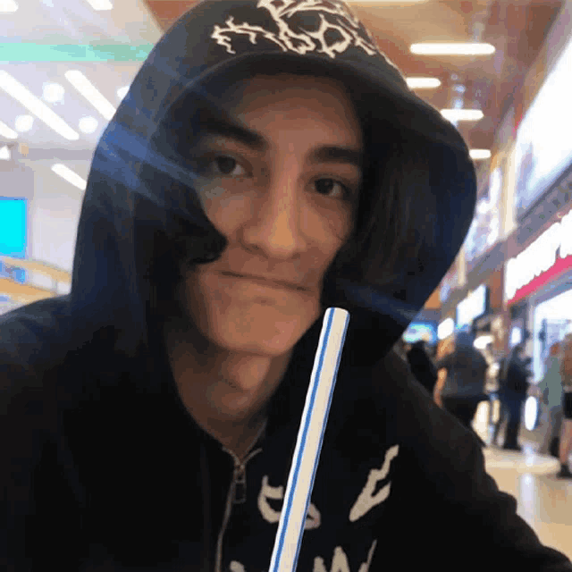 a man wearing a hoodie with the letter a on it is drinking through a straw