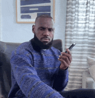 a man in a blue sweater is looking at his phone