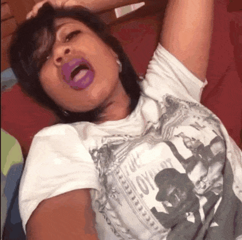 a woman with purple lipstick is wearing a white shirt with a picture of a man on it .
