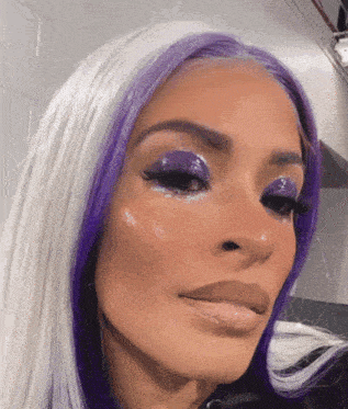 a close up of a woman 's face with purple eye shadow