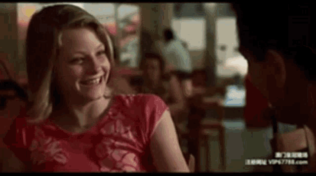 a man and a woman are sitting at a table in a restaurant and smiling at each other .