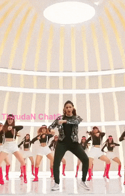 a woman in a silver jacket is dancing with a group of other women