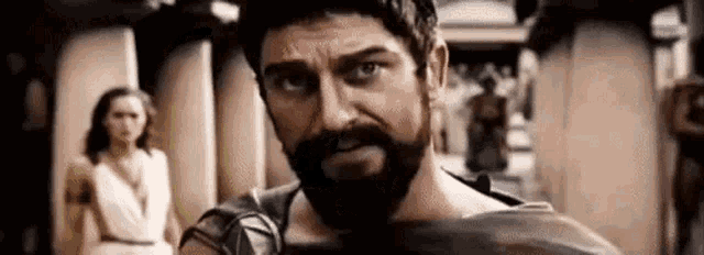 a man with a beard is holding a sword in front of a woman .