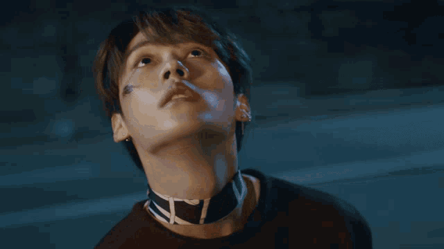 a close up of a person 's face with a choker around their neck with the letter t on it