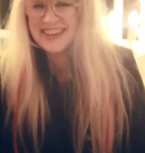 a woman with long blonde hair and glasses is smiling for the camera