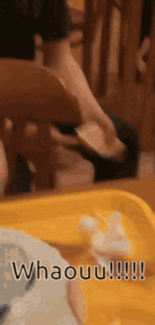a person is sitting on a chair with their foot on a yellow tray with the words whaouu written on it
