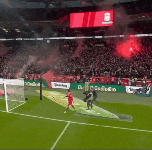 a soccer game is being played in a stadium with a liverpool sign in the background