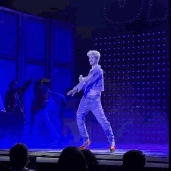 a man is singing into a microphone on a stage while dancing .