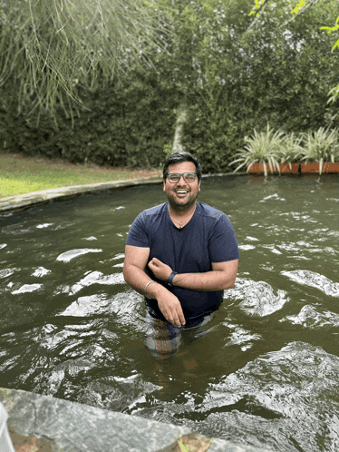 a man in a blue shirt is standing in a pond