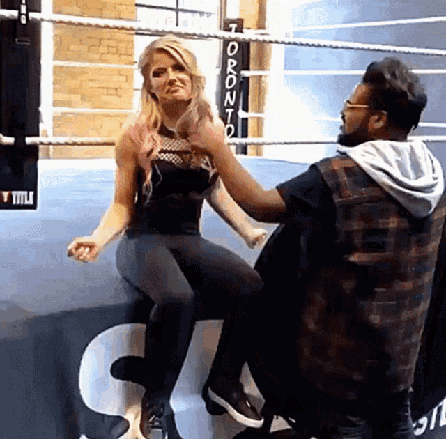 a woman sitting on the edge of a boxing ring with toronto written on the ropes