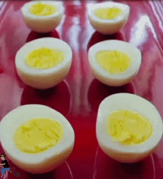 a red plate topped with hard boiled eggs cut in half on a table .