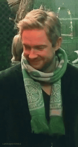 a man wearing a green and white scarf with a celtic design on it