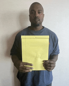 a man in a blue shirt is holding up a yellow pad of paper
