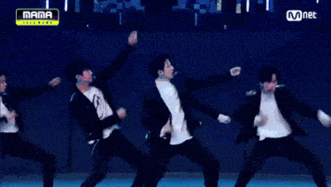 a group of young men are dancing on a stage in front of a mnet logo .