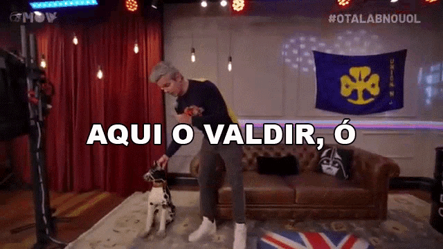 a man standing next to a couch with the words aqui o valdir o written on the screen