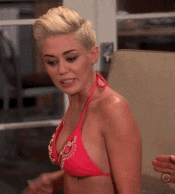 a blonde woman in a red bikini is sitting on a couch