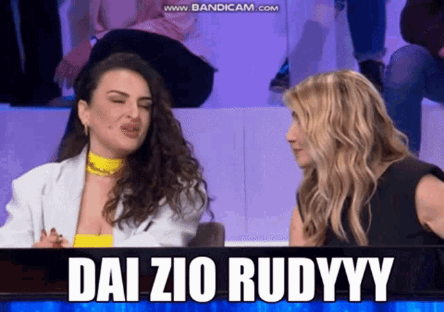 two women sitting in front of a screen that says daizio rudyy