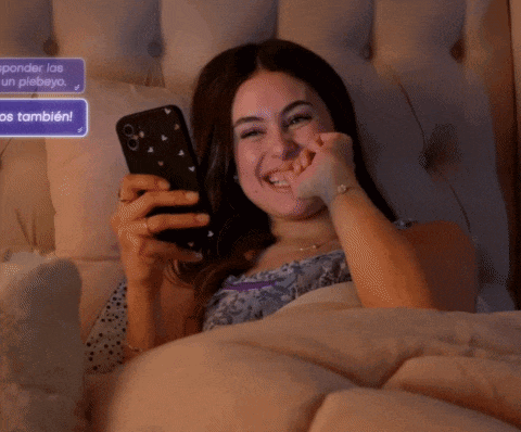 a woman laying on a bed looking at her phone with a message that says ' ineidmot ' on it
