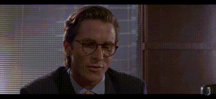 a man wearing glasses and a suit is sitting in front of a window and the word impressive is written on the screen .