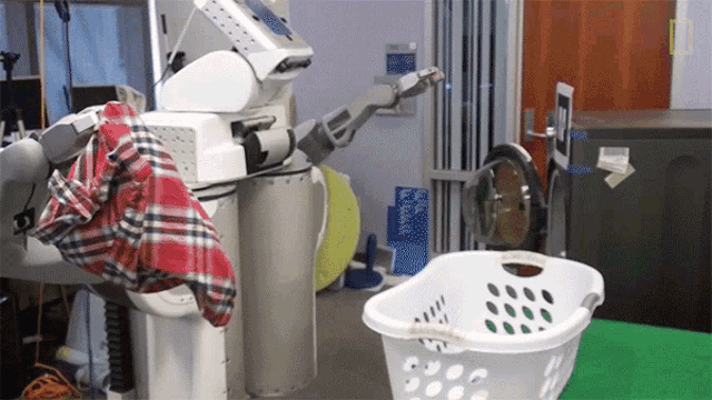 Robô recolhendo as roupas sujas na lavanderia e colocando-as na máquina.