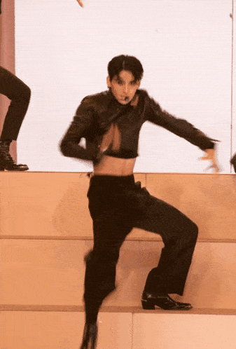 a man in a crop top and black pants is dancing on a stage