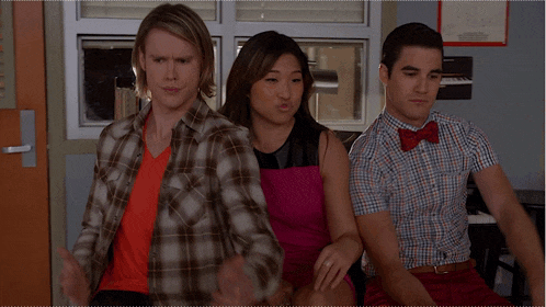 a man in a plaid shirt is sitting next to a woman in a pink dress and a man in a red bow tie