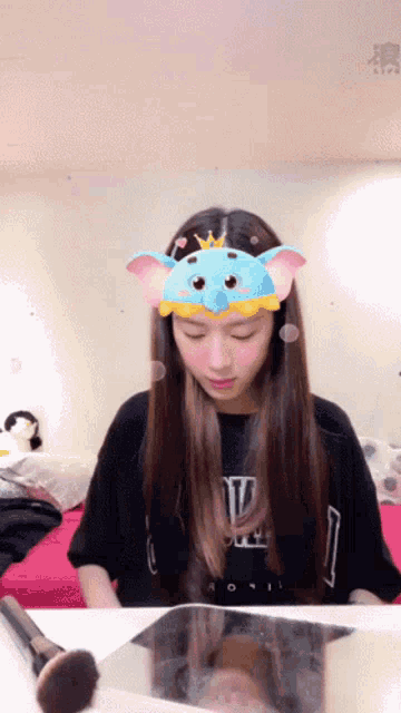 a girl wearing a blue elephant headband looks down at something