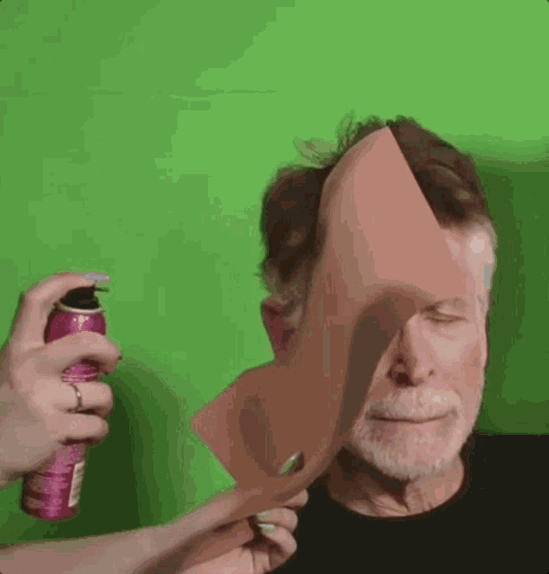 a man with his eyes closed is being sprayed with a can of hair spray