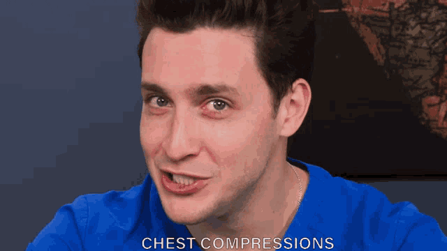 a man wearing a blue shirt with the word chest compressions on the bottom