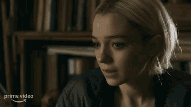 a woman says i 'm gonna go in front of a book shelf