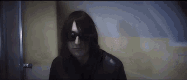 a man with long hair wearing sunglasses and a black jacket