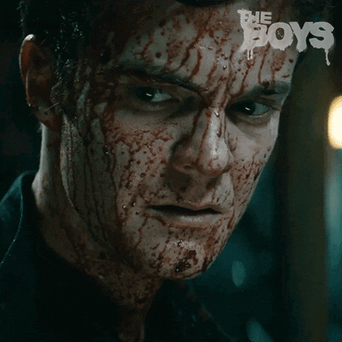 a close up of a man 's face with blood on it and the words the boys behind him