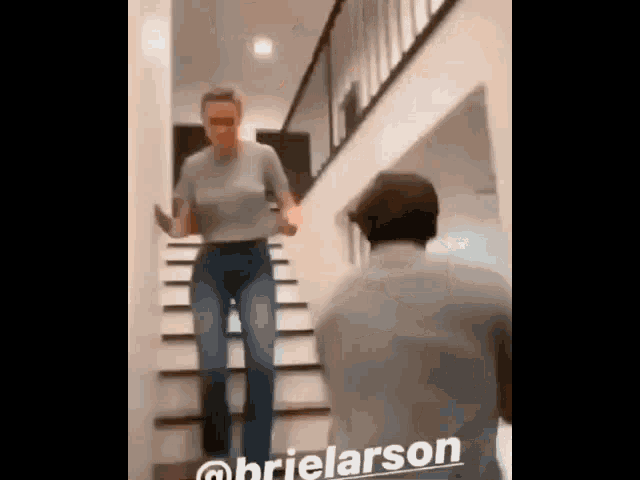 a woman is walking down a set of stairs while a man stands behind her .
