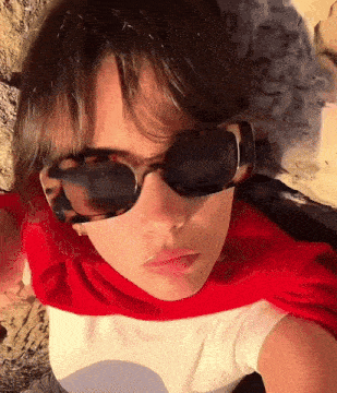 a girl wearing sunglasses and a red cape