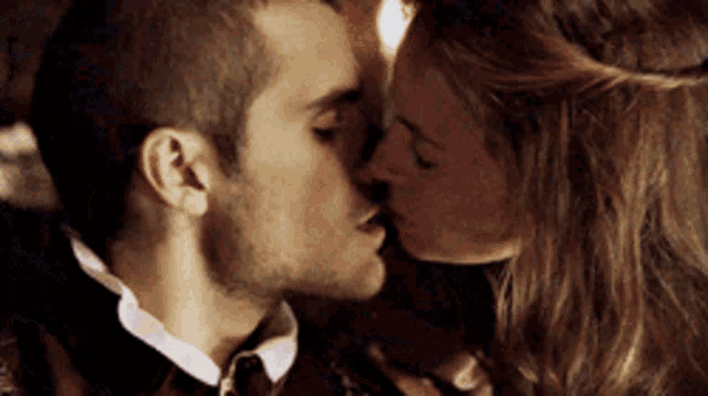 a man and a woman are kissing in a room