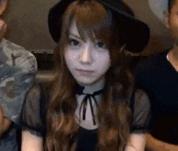 a woman wearing a hat and a black dress is sitting in front of a man .