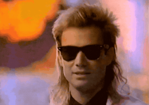 a man with a mullet wearing sunglasses and a white jacket