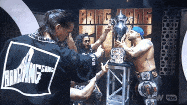 a group of wrestlers are holding a trophy in front of a banner that says bang gang