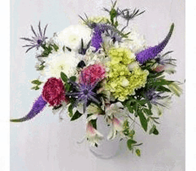 a vase filled with lots of different types of flowers on a table .