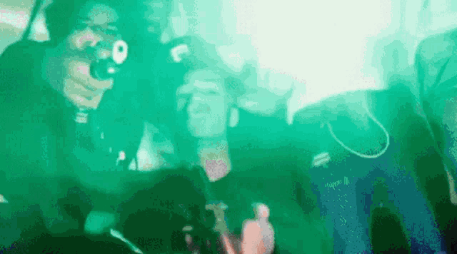 a man is holding a gun in a green light while another man takes a picture of him .