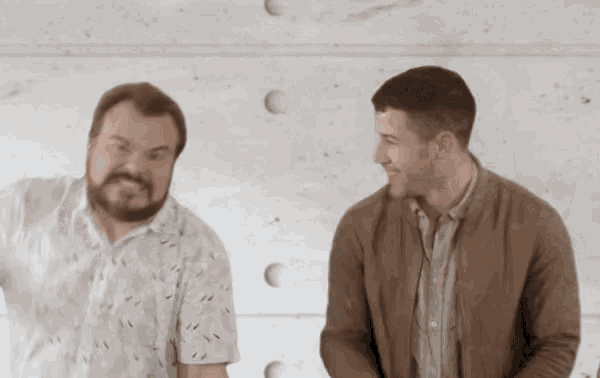 two men are standing next to each other and smiling .