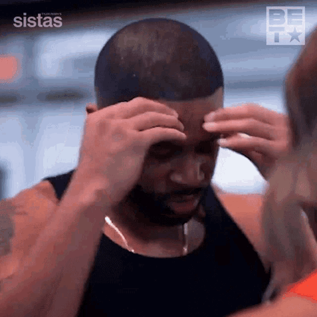 a man with a beard is rubbing his forehead with his hands while a woman looks on .