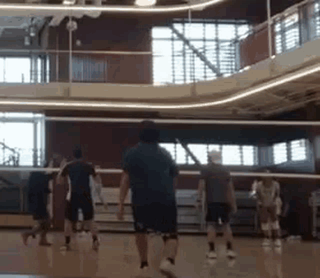 a group of men are playing volleyball on a court in a gym .