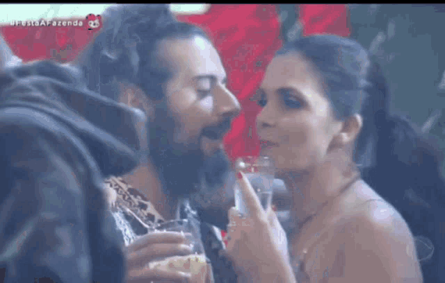 a man and a woman are kissing while holding glasses of wine .