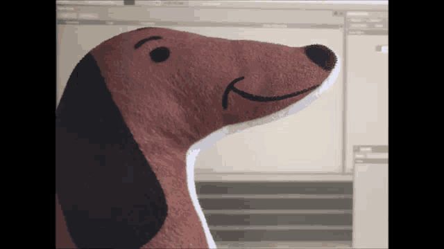 a stuffed dog is sitting in front of a computer monitor