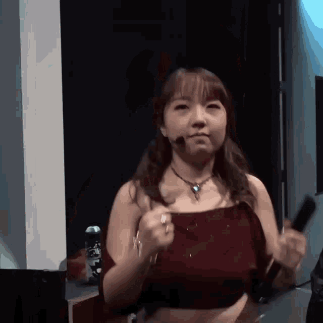 a woman wearing a red top and a necklace is holding a microphone in her hand .